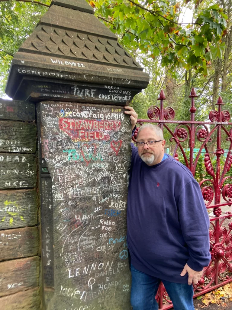 Outside the gates to Strawberry Fields in Liverpool. It is a must stop photo opportunity on your Beatles tour. The famous ornate red iron gates at Strawberry Fields, a must-visit photo spot on a fab-four-liverpool-beatles itinerary.