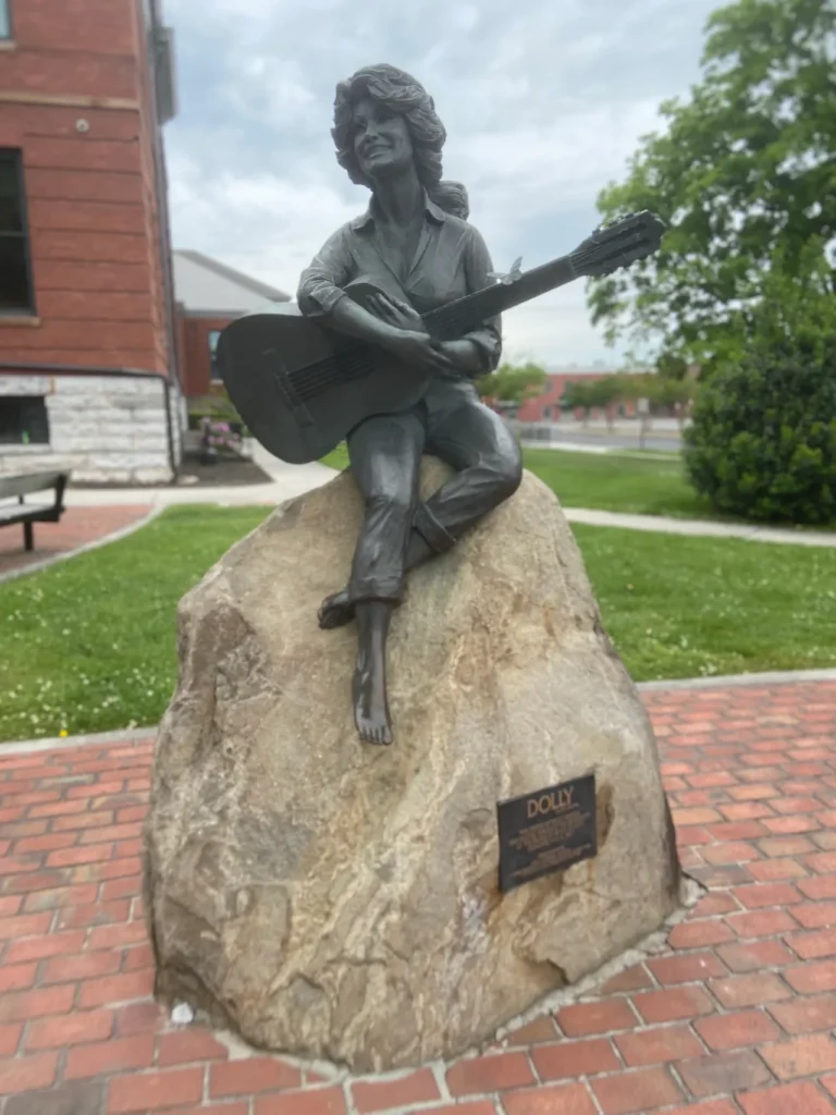 Statue of a young Dolly Parton, the most famous person from the Pigeon Forge / Gatlinburg area. The historic bronze statue of a young Dolly Parton outside the courthouse, a popular stop on a gatlinburg-pigeon-forge-vacation.
