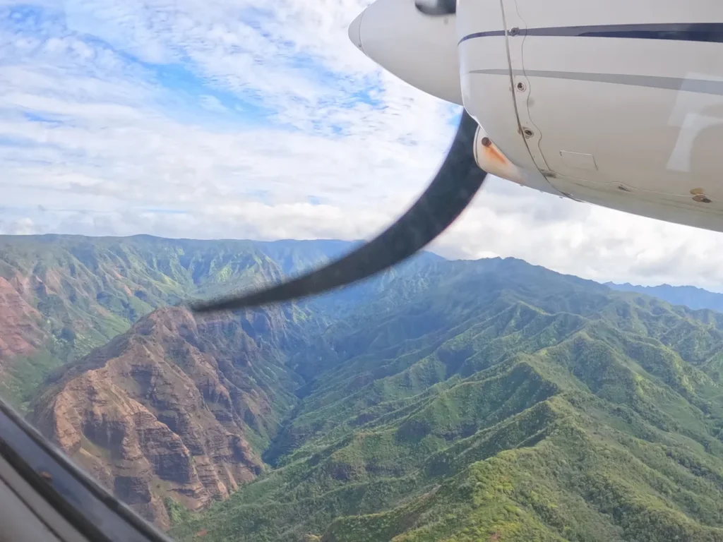 A tourist helicopter flying over the island hills as seen from our vantage point on a private air tour Kauai.