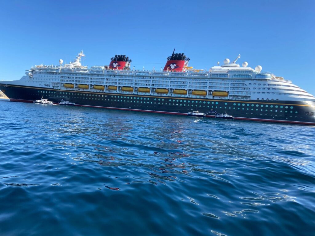 Disney Cruise ships are not floating theme parks. They offer a variety of options for adults, looking to relax and enjoy the very best from a premier cruise line company. A majestic close-up view of a classic Disney cruise ship hull sitting on the blue ocean water from our Disney cruise for adults guide.