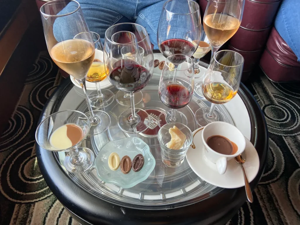 One of the many offerings for adults is the wine pairings class, giving you a chance to sample of variety of wines along with chocolate, cheese and more. A selection of wine glasses, chocolates, and cheese arranged on a tray during an onboard wine pairings class on a Disney cruise for adults.