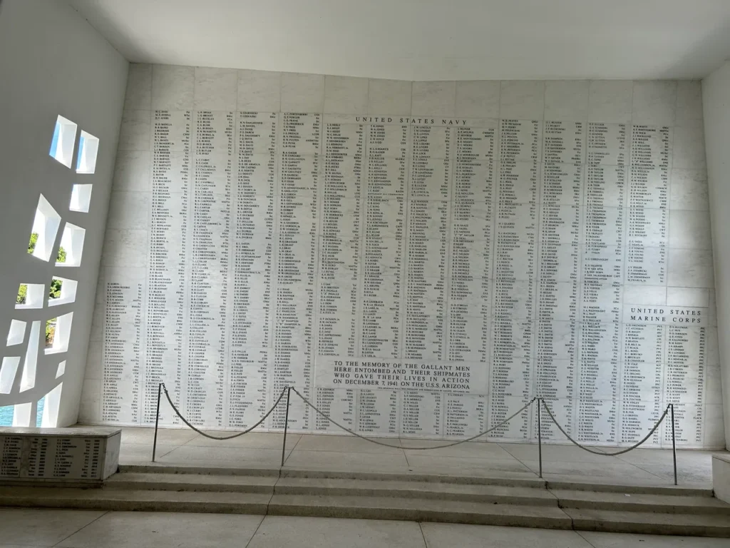 Inside the floating USS Arizona Memorial is a somber memorial. The marble wall lists all the names of those lost during the attack. The somber marble remembrance wall listing the names of lost sailors inside the Pearl Harbor Memorial Hawaii.