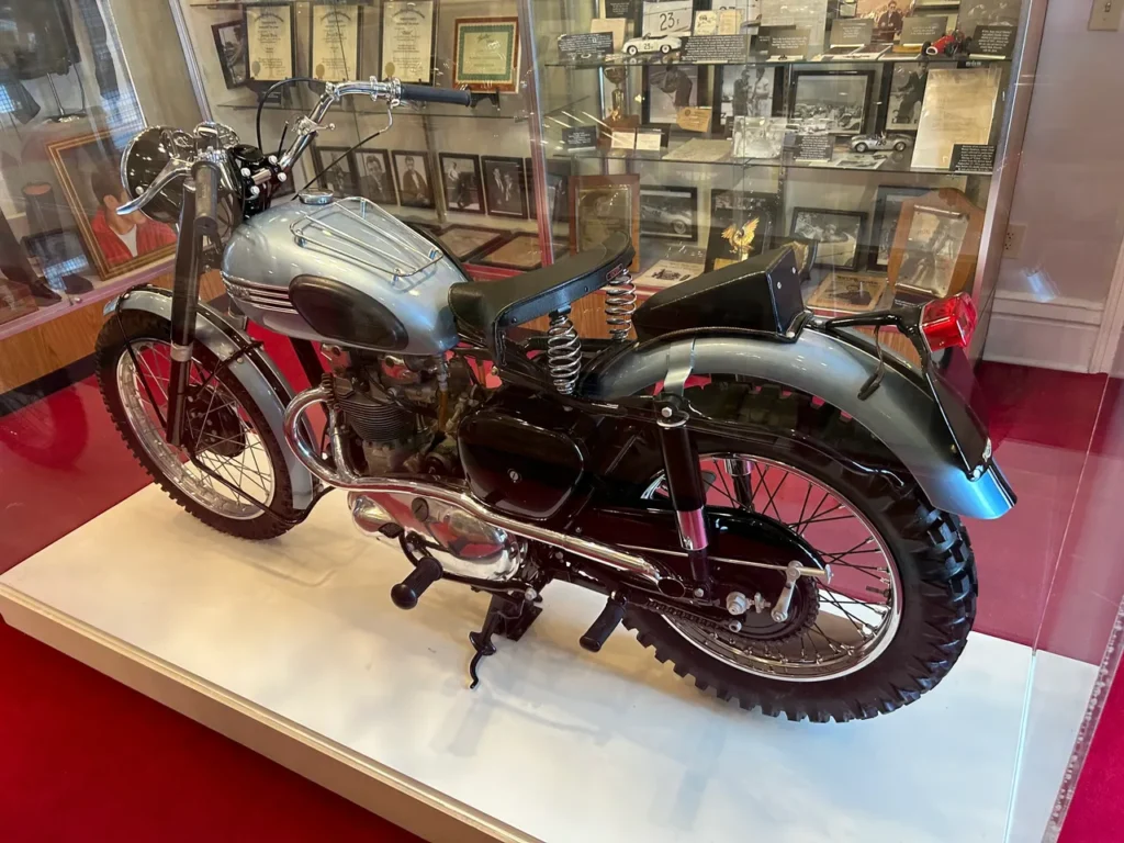 James Dean loved speed, with fast cars and fast motorcycles. ABOVE: On display at the museum is his 1947 Czech 125cc motorcycle. BELOW: One of the museum’s prized pieces, Dean’s 1955 Triumph TR5 Trophy 500cc motorcycle. A beautifully restored vintage blue 1955 Triumph TR5 Trophy 500cc motorcycle on display behind glass at the James Dean Museum in Indiana.