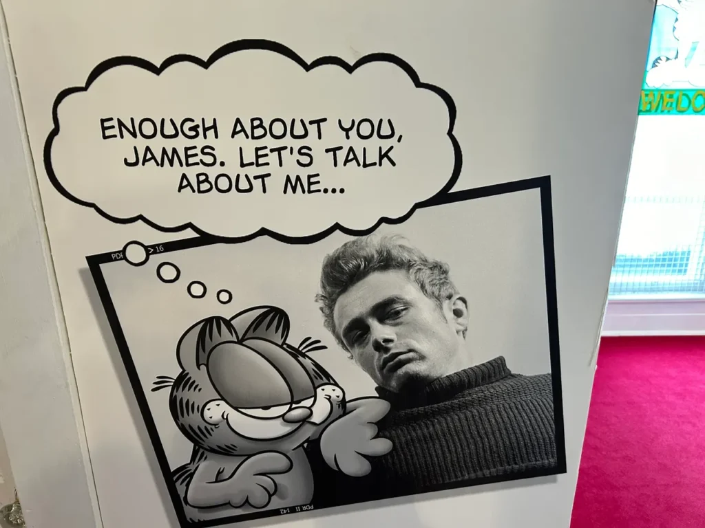 Two most famous residents from Fairmount, Indiana are James Dean and Garfield the Cat. In addition to the large Dean exhibit, there is a small exhibit paying tribute to Garfield and creator Jim Davis who was born in Fairmount too. A framed comic illustration of Garfield the cat next to James Dean on display at the James Dean Museum in Indiana.