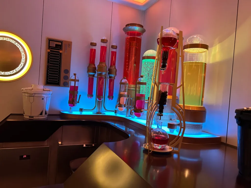 The futuristic bar counter featuring glowing colorful liquid canisters and immersive galactic decor inside the Star Wars Hyperspace Lounge from our Disney Wish dining guide.