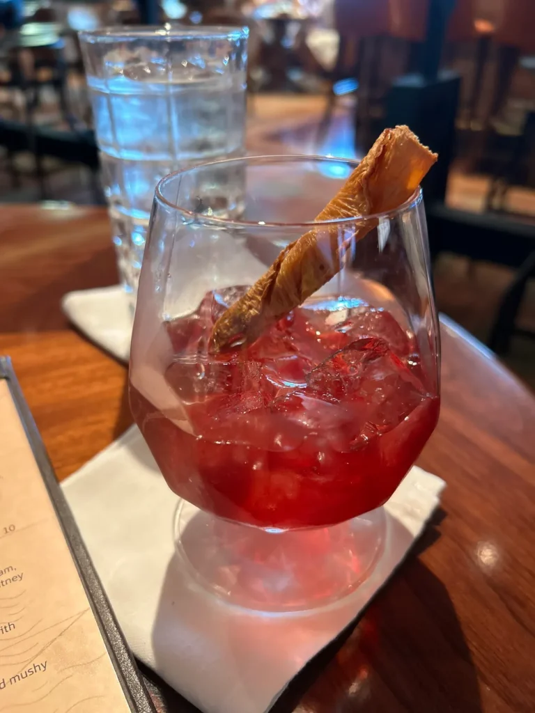 A close-up of an Old Fashioned Glogg cocktail served over ice at the Keg & Compass pub, featured in our Disney Wish dining guide.