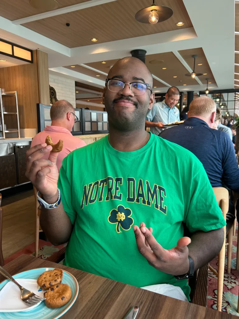 A guest holding a freshly baked chocolate chip cookie at the Marceline Marketplace buffet featured in our Disney Wish dining guide.