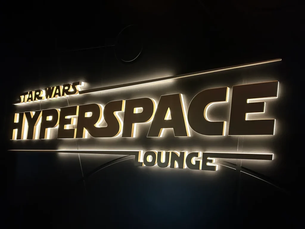 The sleek, illuminated gold and white Star Wars Hyperspace Lounge sign from our Disney Wish dining guide.