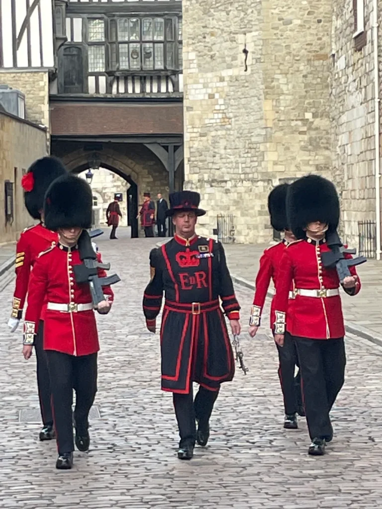An armed escort along with the Duty Yeoman Warder perform a 700 year old tradition to open up the Tower of London. An armed military escort marching with a Yeoman Warder during the morning opening ceremony at the Tower of London planning guide site.
