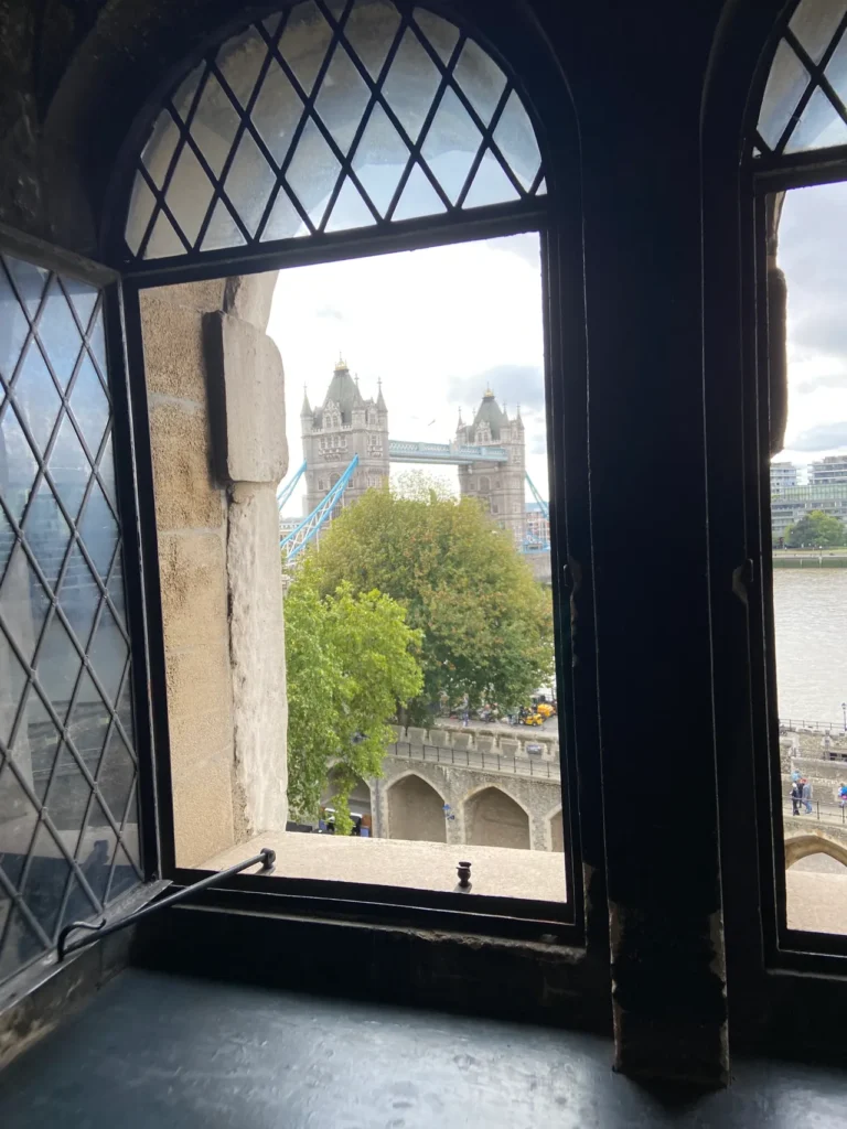 One of the windows in the Tower of London, providing a beautiful view of the London skyline and the Tower Bridge. A view of Tower Bridge and the London skyline framed perfectly by an open stone window at the Tower of London planning guide fortress.