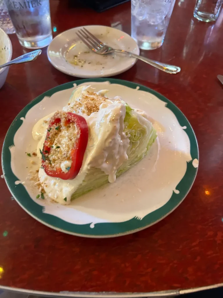 House-made blue cheese dressing tops the wedge salad at Bonge’s. A crisp iceberg wedge salad smothered in house-made blue cheese dressing and topped with a red pepper ring at Bonge's Tavern Indiana.