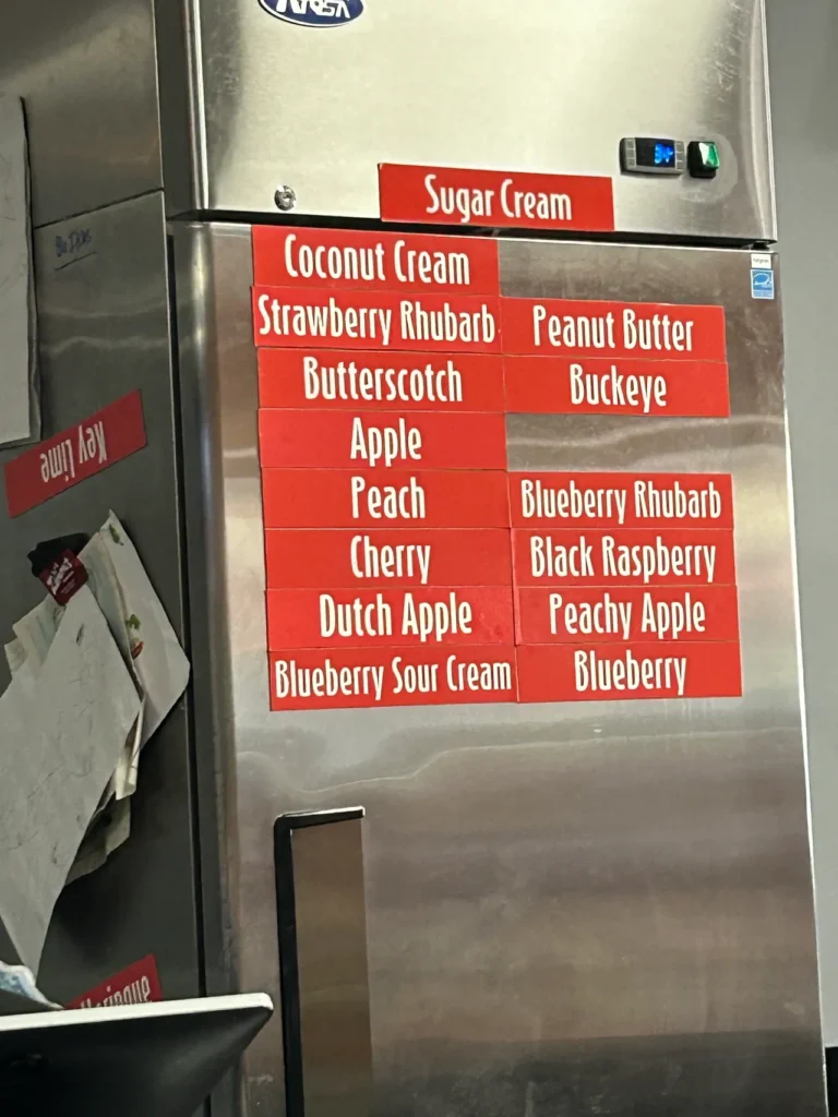 You come to Nick’s for the pork tenderloin but you stay for the pie. Their daily selection is displayed on their cooler, just behind the cash register. The daily menu board of homemade pie flavors on display at Nick's Kitchen, a classic smalltown diner Indiana.