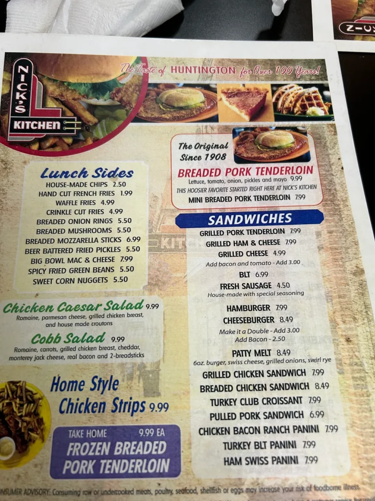 The lunch menu from Nick’s Kitchen in downtown Huntington, Indiana. Known as the birthplace of the breaded pork tenderloin sandwich, they offer a wide variety of options for breakfast and lunch. The printed breakfast and lunch menu displaying pricing and sandwich options at Nick's Kitchen, a classic smalltown diner Indiana.