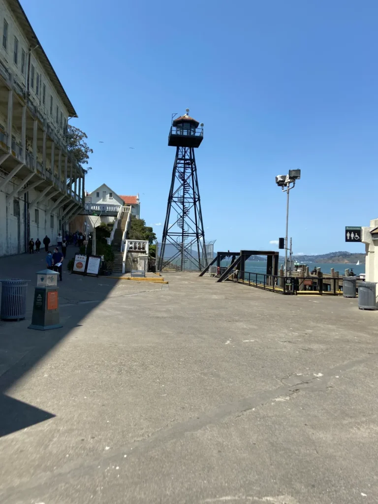 The bottom of the hill, near the pier where you come on Alcatraz Island. You can walk up the steep hill yourself or take the tram which will drop you off at the prison. The entry path at the bottom of the hill near the arrival pier at Alcatraz Prison San Francisco.