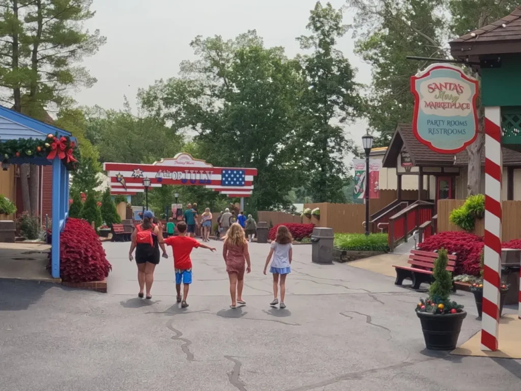 Holiday World features various holiday themes throughout the park. Christmas, Halloween, 4th of July and Thanksgiving all offer unique opportunities for family fun. Families walking down the main pathway toward the patriotic 4th of July section entry gates at Holiday World Santa Claus Indiana.
