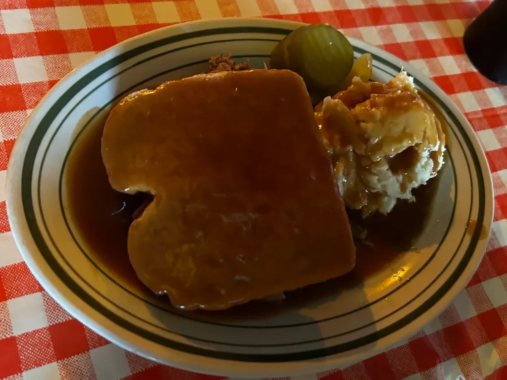 Tony Packo's roast beef sandwich, which is really a beef Manhattan is served over their hand prepared mashed potatoes along with their spicy pickles. A traditional roast beef sandwich Manhattan platter served over mashed potatoes with gravy and spicy pickles at Tony Packo’s Toledo.
