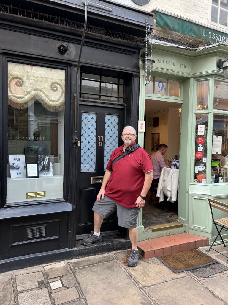 Ted Lasso's apartment on the Paved Court in Richmond. A traveler posing outside the famous black front door of Ted Lasso's apartment on Paved Court, a highlight of our Richmond England Ted Lasso walking guide.
