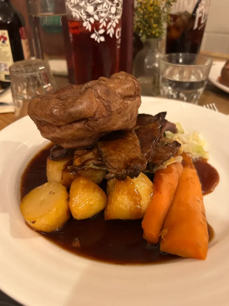 The traditional sirloin of beef Sunday roast served at the Prince's Head in Richmond, UK. It is topped by the light and fluffy Yorkshire pudding. A traditional sirloin of beef Sunday roast topped with a large Yorkshire pudding at The Prince's Head, the famous Ted Lasso pub in Richmond.