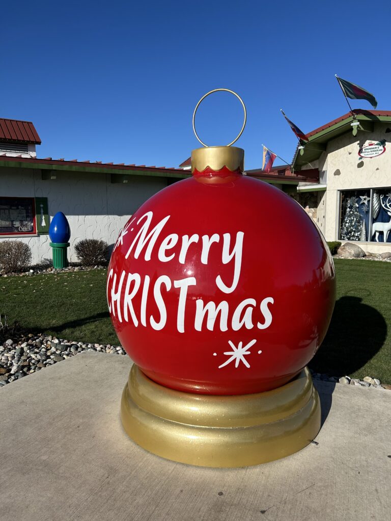 A massive, iconic red giant ball ornament decoration displayed outside Bronner's Christmas Wonderland during a Frankenmuth Michigan Christmas tour.