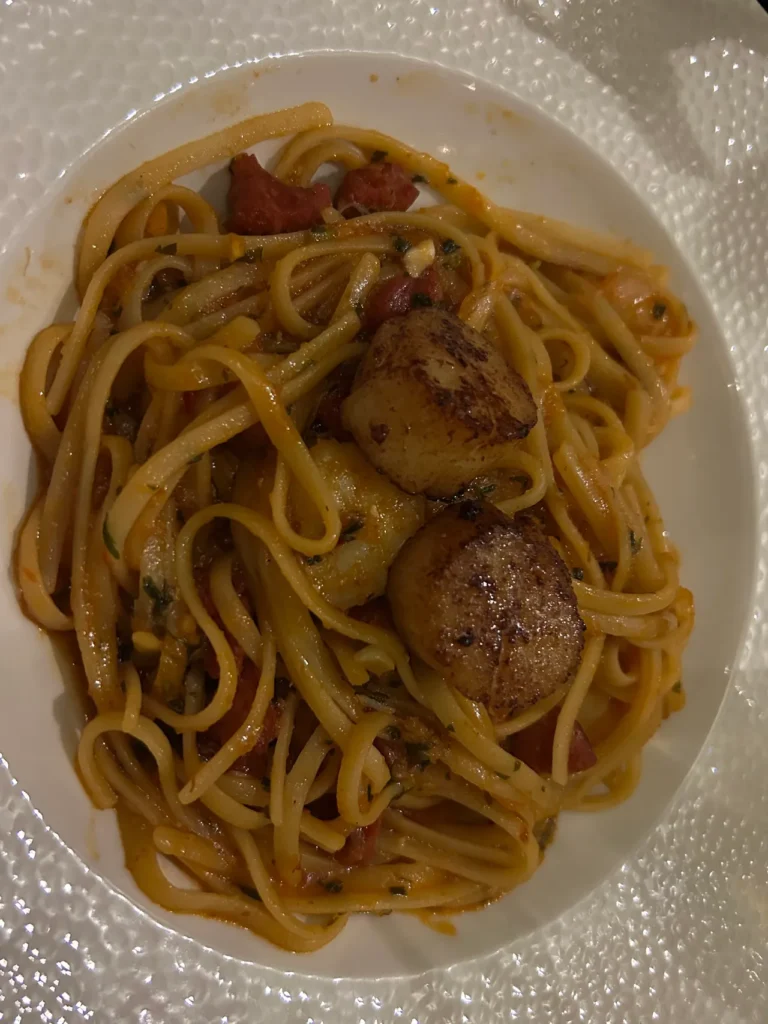 The menu at The Sheep Heid Inn in Edinburgh offers a wide variety of options. From burgers and steaks, to some unique seafood options like this king prawn, crab and ortiz chorizo over linguine with scallops, made with white wine, tomato with a garlic and chili sauce dish. The king prawn crab and chorizo dish with pan-seared scallops over linguine, a culinary highlight at the Sheep Heid Inn Edinburgh.