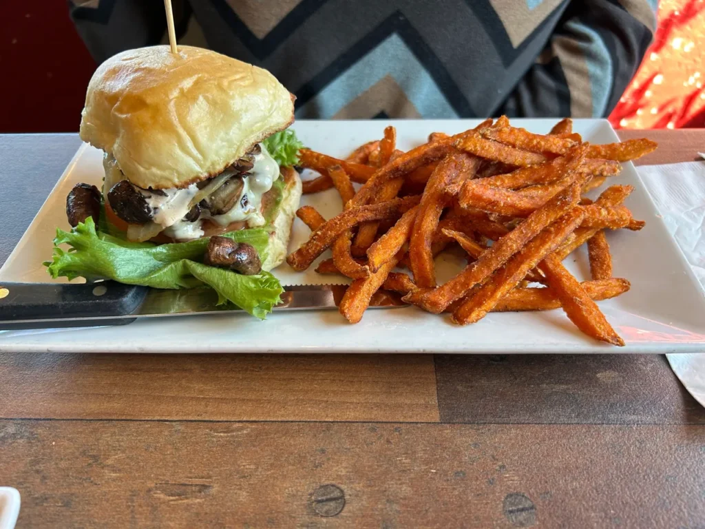 GAS - Full Service Restaurant offers amazing gourmet burgers, including this mushroom Swiss burger served with sweet potato fries. A juicy gourmet mushroom Swiss burger served with a mountain of seasoned sweet potato fries at GAS Full Service Restaurant, a highlight of our St. Augustine restaurants guide.