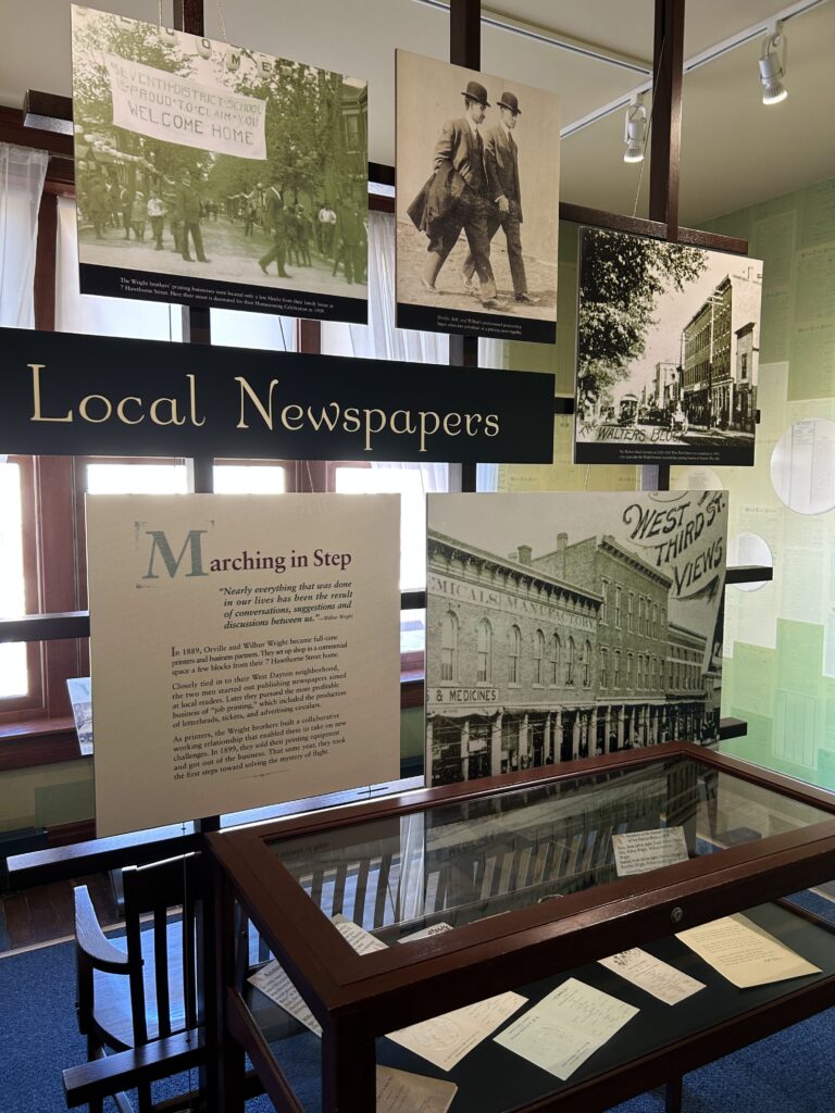 Orville and Wilbur Wright were quite the businessmen. Before taking flight, they were successful printers and newspaper publishers in the Dayton area. Historical printing press equipment and biographical displays inside the Wright Brothers exhibit, highlighting Dayton Ohio aviation history.