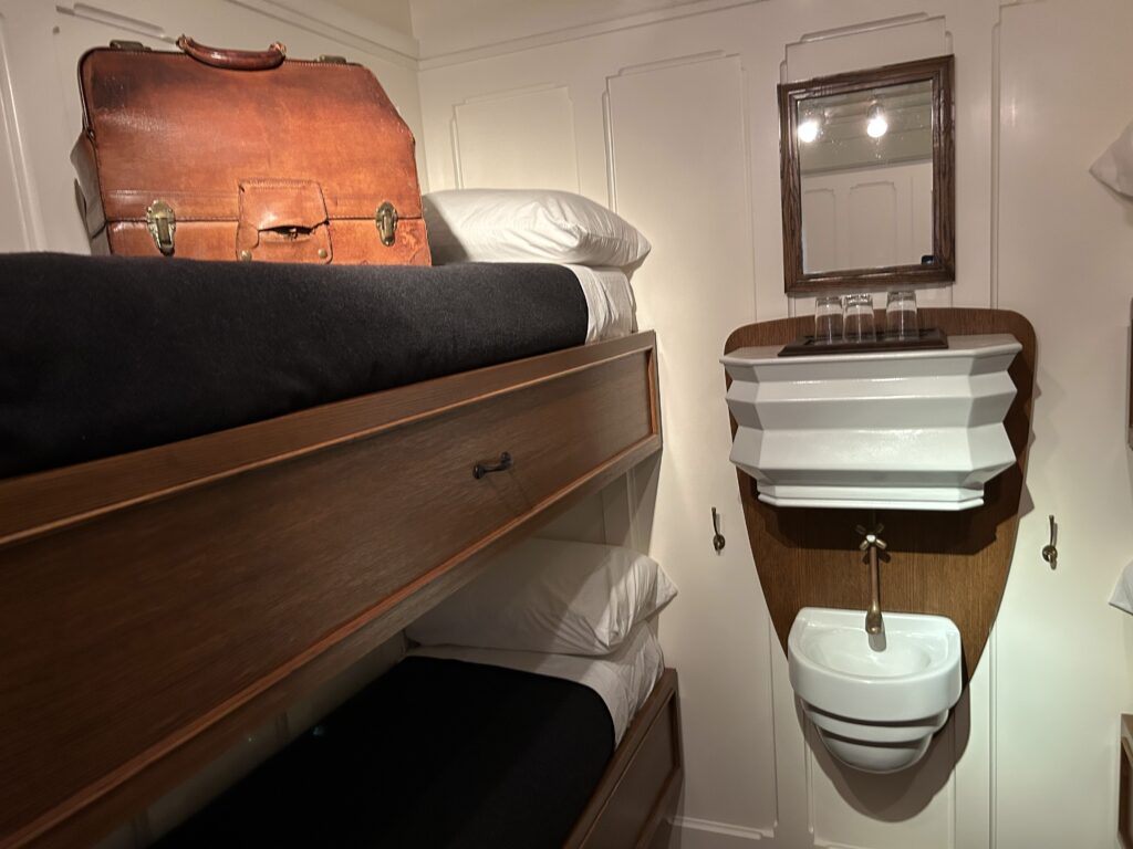 Two sets of bunk beds and a small sink with running water were the amenities of a third class cabin. This exhibit showed the actual space, which seemed cramped by today's standards, but were actually a new standard of comfort in 1914. A replica of a cramped third class cabin featuring two sets of bunk beds and a small white sink at the Titanic Museum Pigeon Forge.