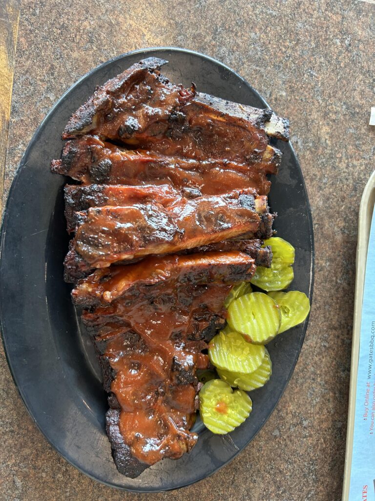 A full slab of ribs drenched in the spicy Gates sauce is a Kansas City tradition. A full slab of smoky ribs drenched in spicy sauce served with pickles on a Kansas City BBQ tour.