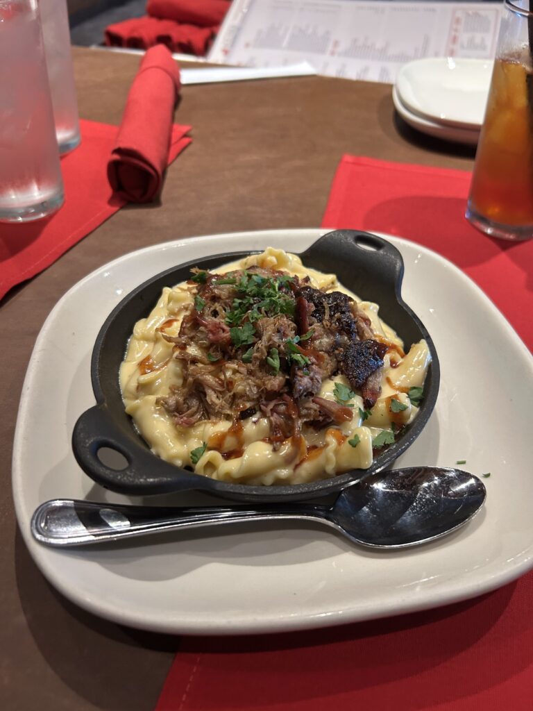 Creamy mac 'n cheese and hickory smoked pulled pork is a perfect combination, and a highlight of the Jack Stack Barbecue menu. The famous baked mac and cheese side dish from Jack Stack featured on a Kansas City BBQ tour.