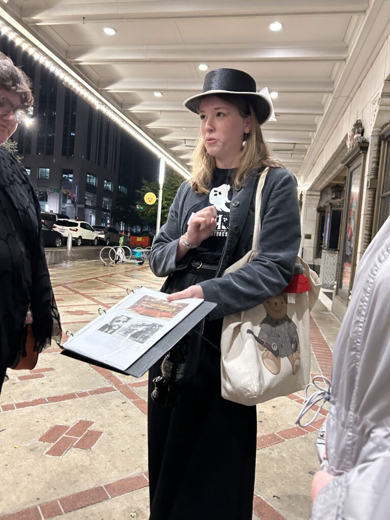 The ghost tour originates in front of the Indiana Repertory Theatre, where you'll learn about its origins and the tragedy that fell on one of its founders. A costumed ghost tour guide standing under the historic marquee of the Indiana Repertory Theatre during a haunted Indy walking tour.