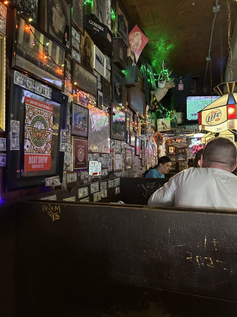 Even though it is a bar, the Thurman Cafe is family-friendly during the day. The atmosphere is relaxed, with the walls decorated with Ohio State memorabilia and signed dollar bills. The lively interior bar area of the Thurman Cafe Columbus Ohio, covered wall-to-wall in signed dollar bills and sports memorabilia.
