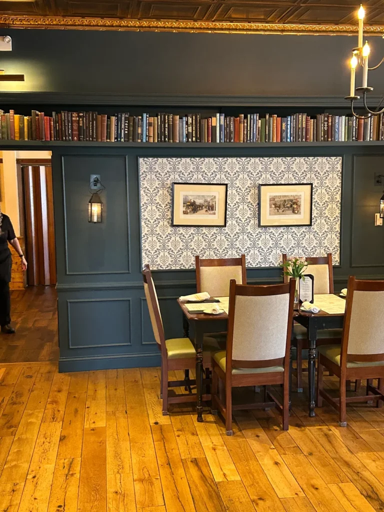 The Charles Dickens dining room is named after the famed British author who visited the Golden Lamb in 1842. The Charles Dickens dining room at the historic Golden Lamb restaurant in Lebanon, Ohio, featuring dark wood built-in bookshelves, patterned wallpaper, and formal dining tables.