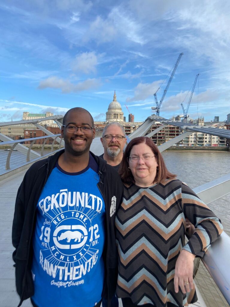 A group of three travelers posing on the Millennium Bridge with St. Paul's Cathedral in the background during a Harry Potter London black taxi tour.