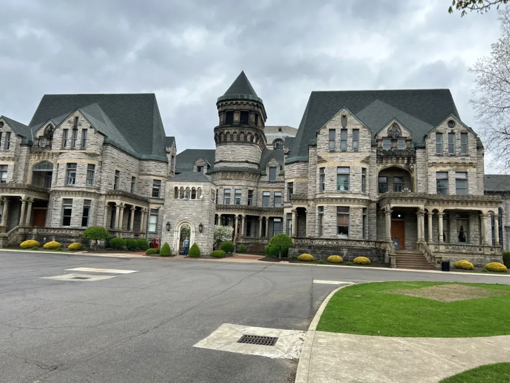 The imposing Romanesque Revival stone entrance of the Ohio State Reformatory in Mansfield, Ohio, featuring castle-like turrets and arched windows. The front stone exterior of the historic Ohio State Reformatory castle structure in Mansfield, Ohio.