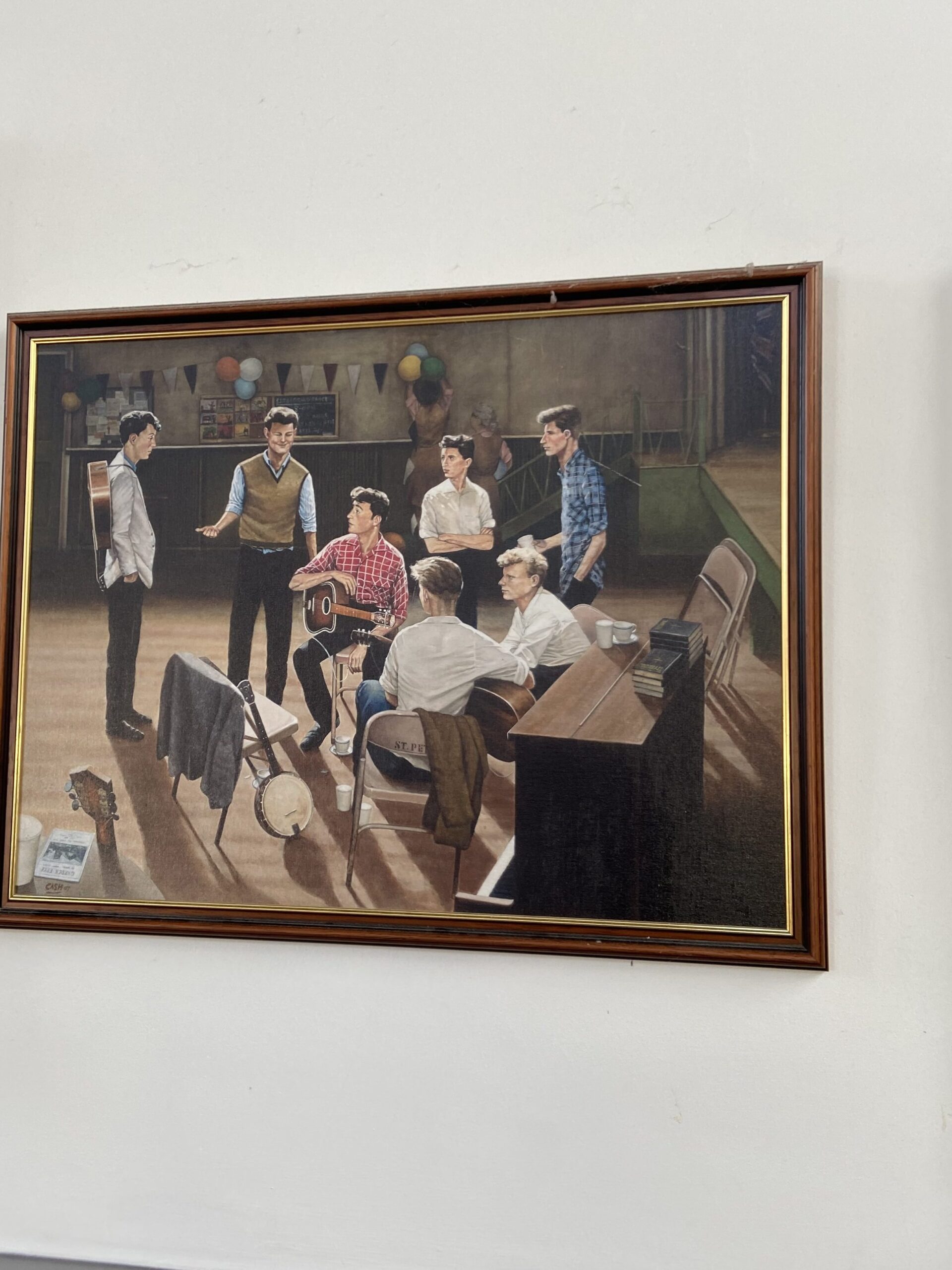 One of the items on exhibit at St. Peter’s Church Hall in Liverpool is this painting depicting the day John Lennon met Paul McCartney. The painting was created by Eric Cash. An oil painting by Eric Cash depicting the historic day John Lennon met Paul McCartney, featured in our Beatles breakup and Disney World history guide.