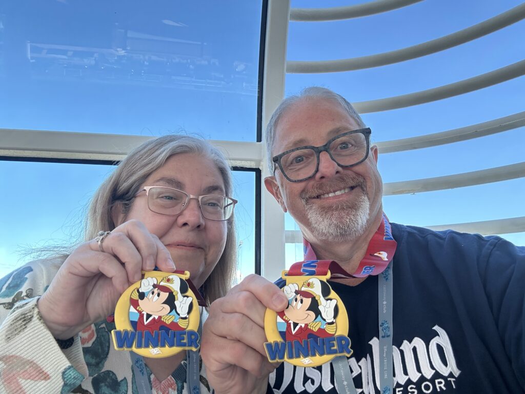 Two guests proudly displaying their winner medals after a victory in a trivia contest, a fun highlight detailed in our Disney cruise tips.