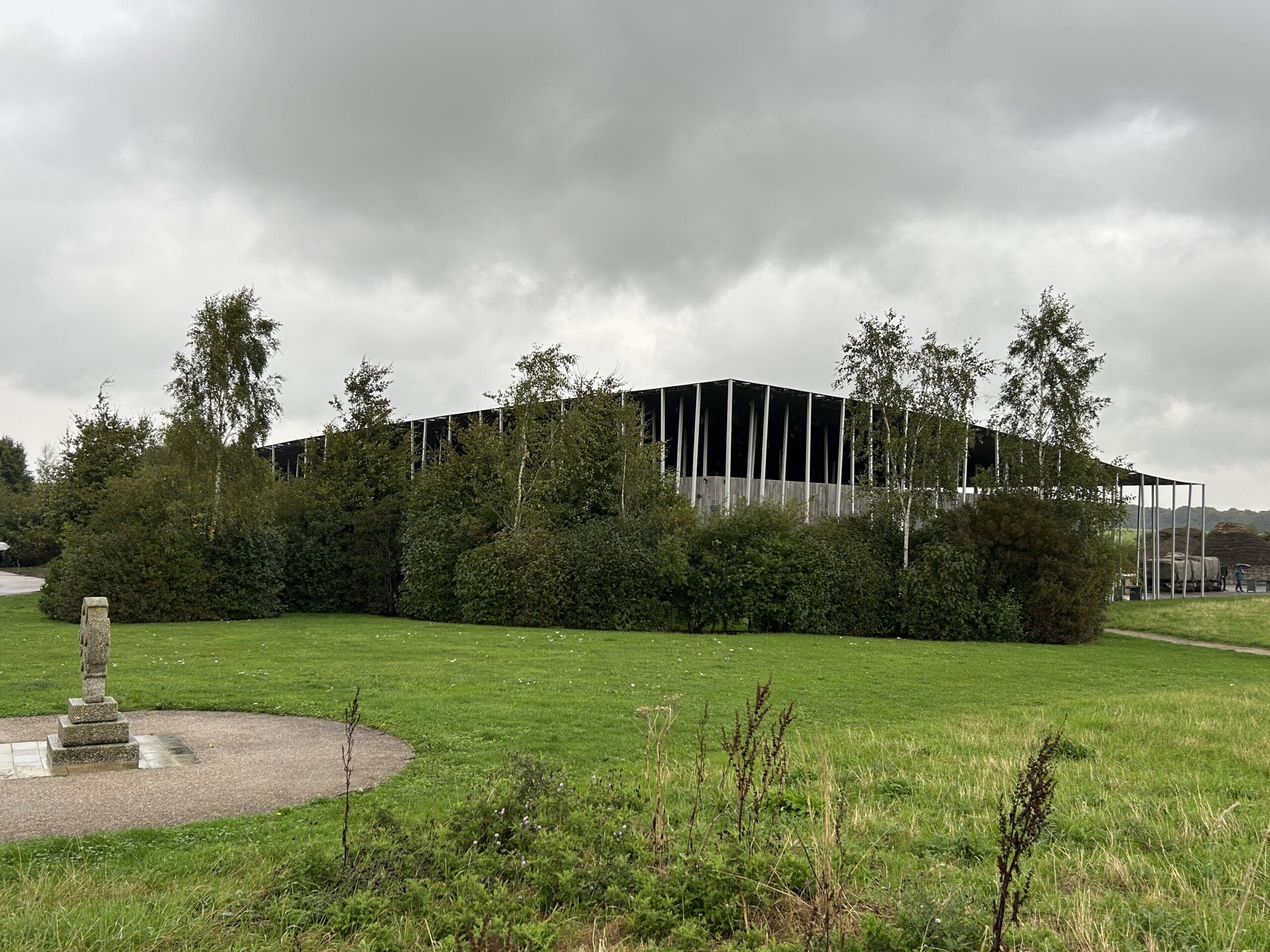 Approaching the visitor's center at Stonehenge which was built in 2013. From there you can catch a tram to the monuments, tour the museum, enjoy a snack or shop the gift shop. Approaching the modern visitor's center building on a Stonehenge vacation itinerary day tour.